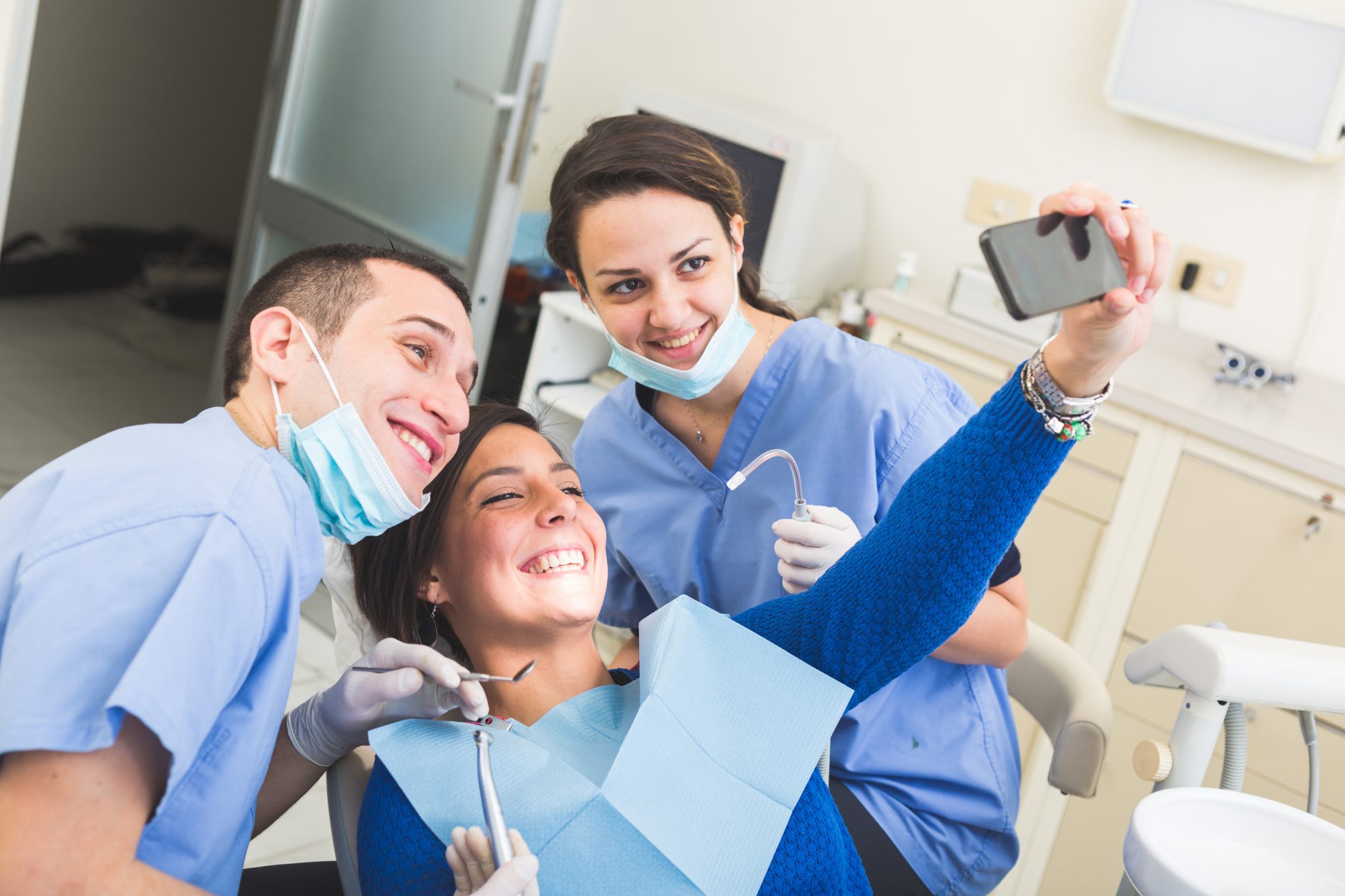 happy patient, dentist and assistant taking selfie all together.